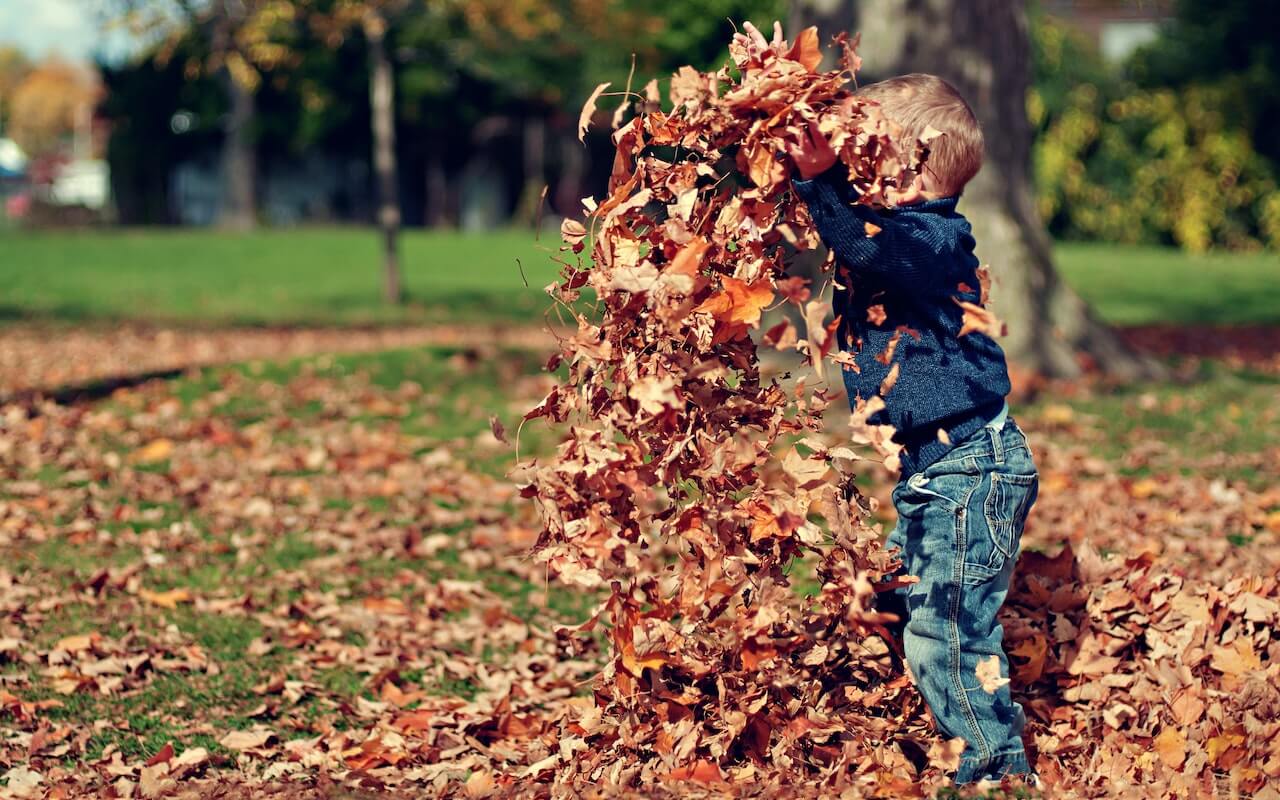 Time in nature provides ample opportunities for kids to get physical activity like this child tossing dried leaves around